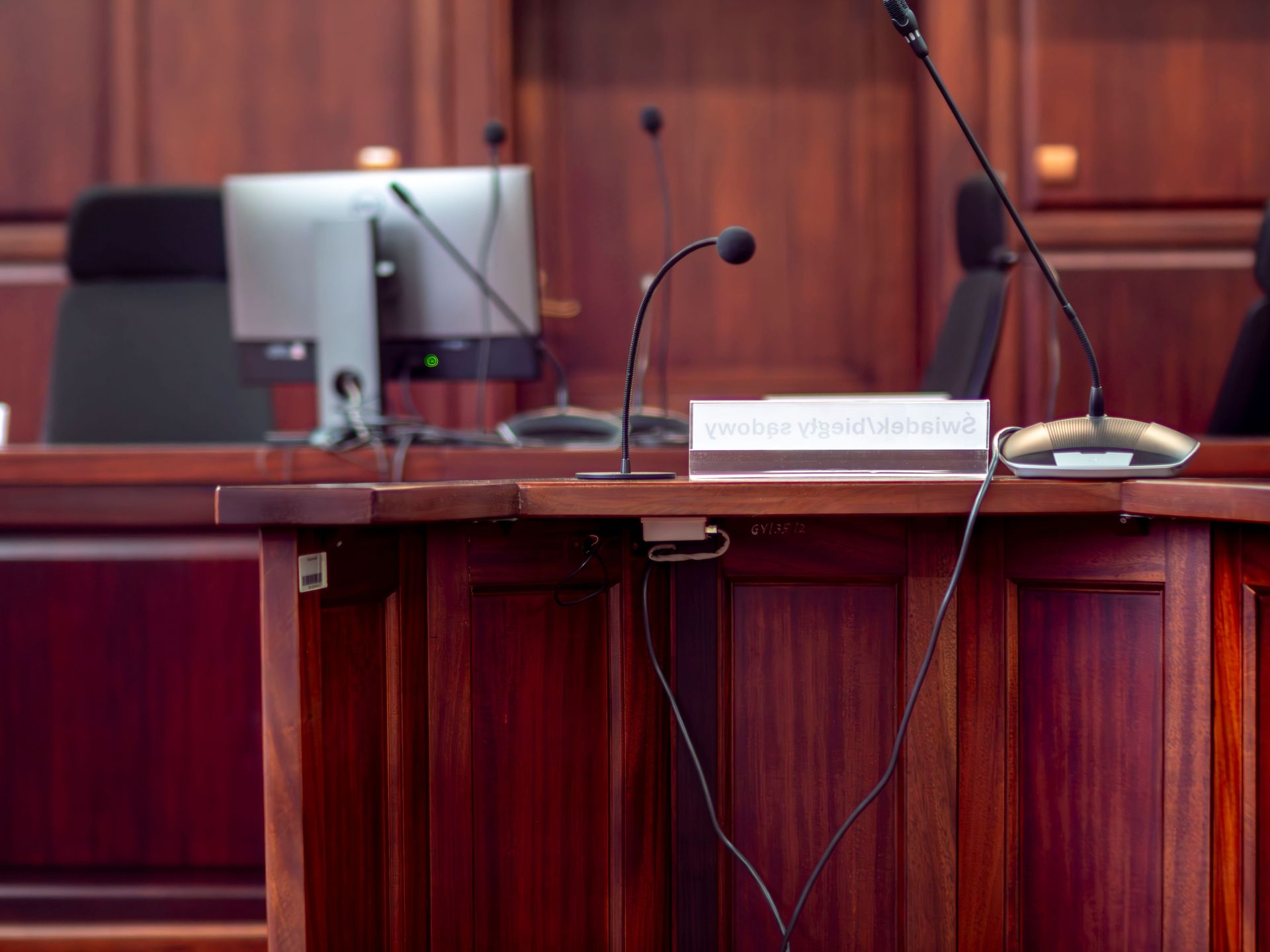 Close-up of a wooden podium with microphones in a Polish courtroom setting.